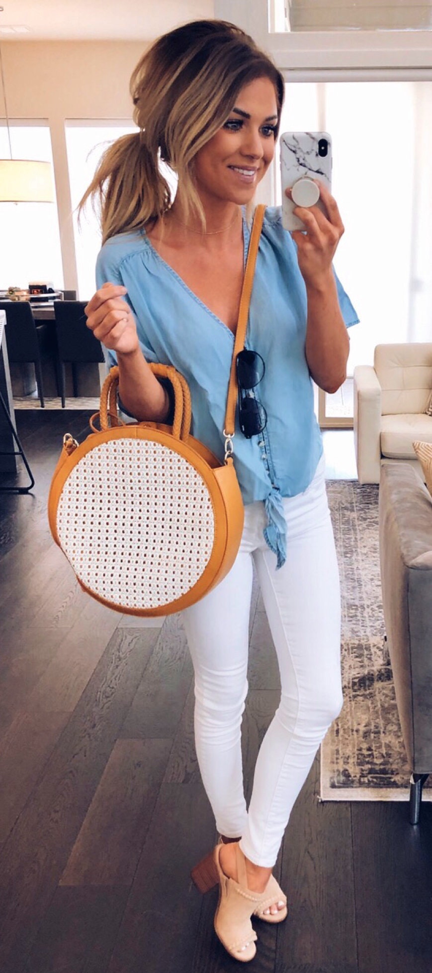 White fitted jeans, blue V-neck shirt and round crossbody bag.