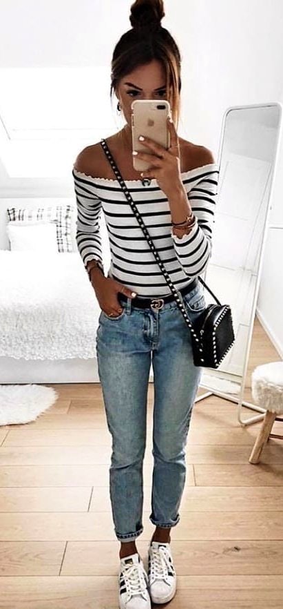White sneakers, white and black striped off-shoulder long-sleeved shirt and blue denim jeans.