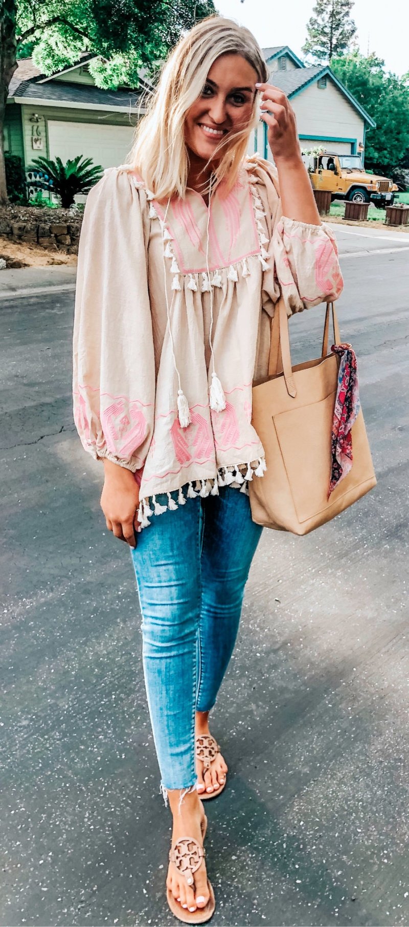 Ankle length blue jeans, white and pink jaboot-sleeve tassel accent top.