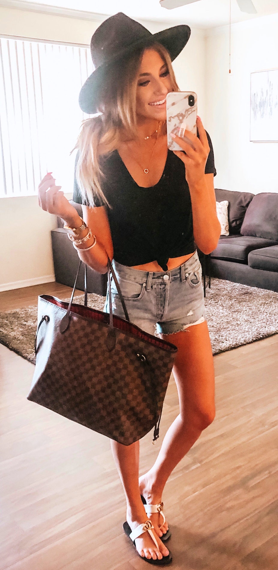 Black crop top, brown flat sandals, gray denim short and brown leather tote bags.