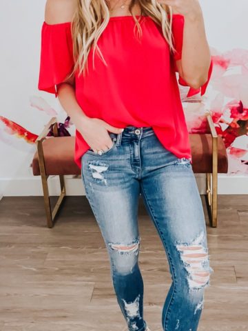 Blue distressed jeans and red off shoulder top.
