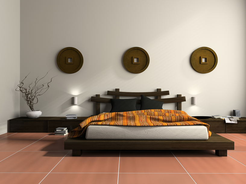 Simple dark wood platform bed on red tile floor with white walls