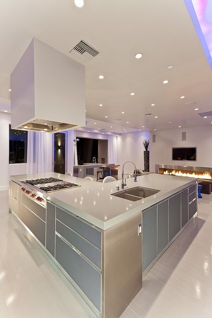 Coloured lighting adds an opulent quality to a white kitchen