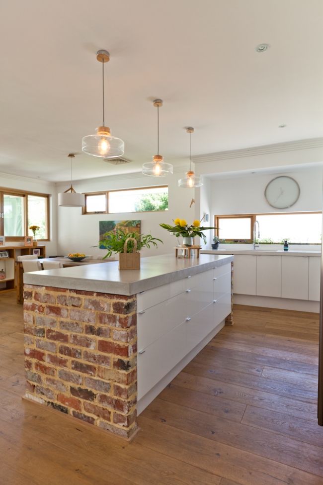 Warm red brick creates a more industrial feel to a clean white kitchen.