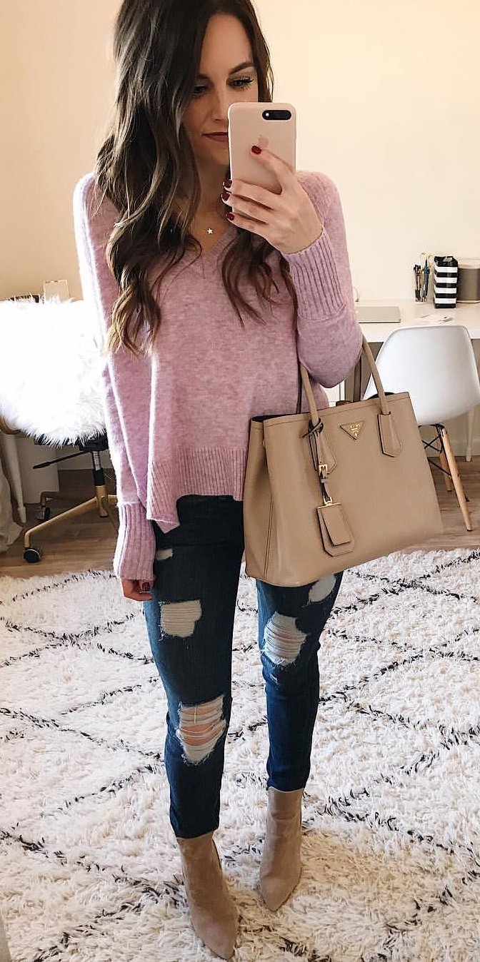 women's pink v-neck sweater, distressed blue denim jeans, brown leather handbag, and pair of brown suede booties