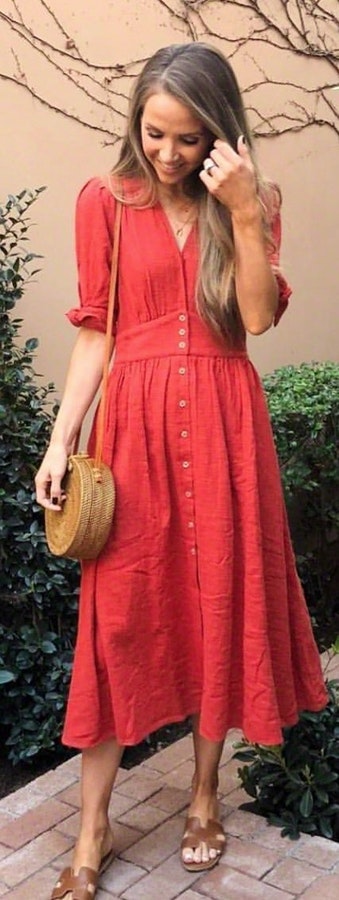 Pink button-up long-sleeved dress carrying brown leather crossbody bag.
