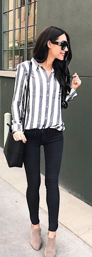 White and black striped collared button-up long-sleeved shirt and black skinny jeans carrying black shoulder bag.