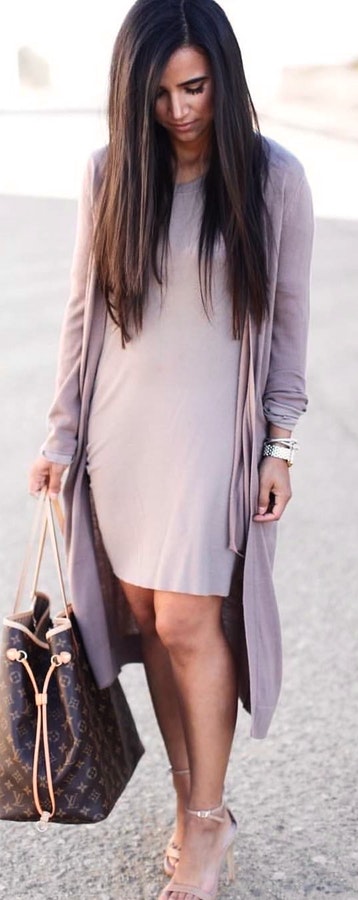 Woman in gray dress with open cardigan holds brown Louis Vuitton Monogram bag.
