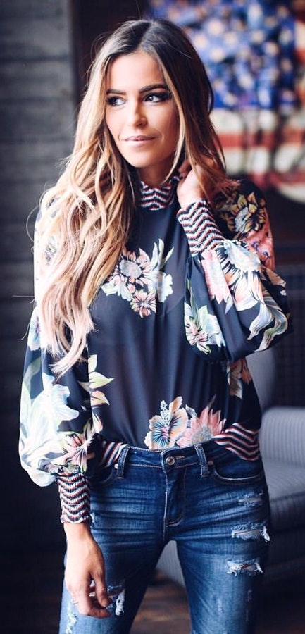 woman wearing black and blue floral long-sleeved top and distress blue denim skinny jeans.