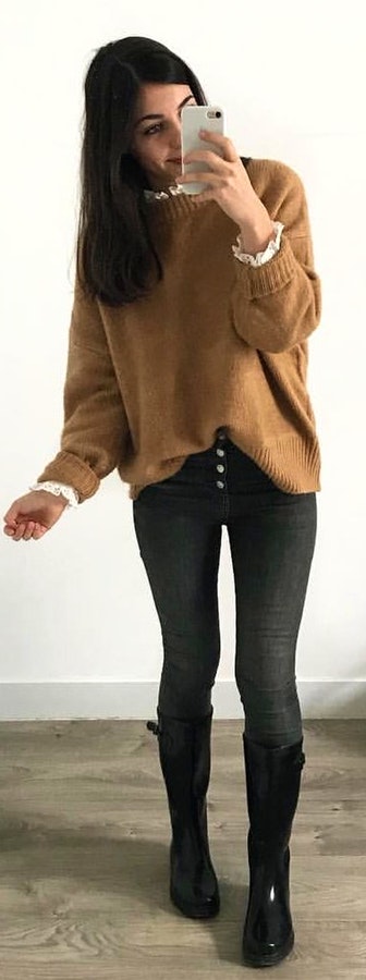 woman wearing brown sweater holding white Android smartphone.