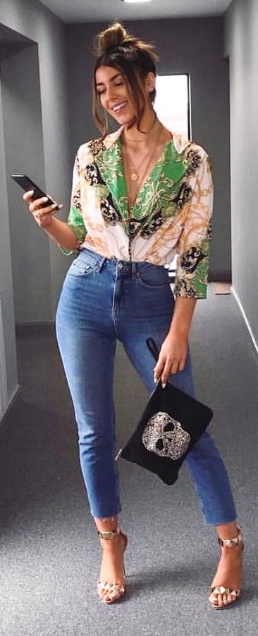 Green and black long-sleeved blouse with blue denim jeans and black purse outfit.