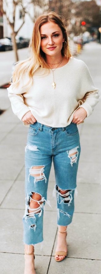 Grey boat-neck sweater and disstressed denim jeans with high heels.
