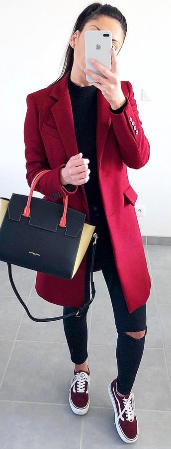 Red coat and distressed black denim jeans carrying black leather tote bag.