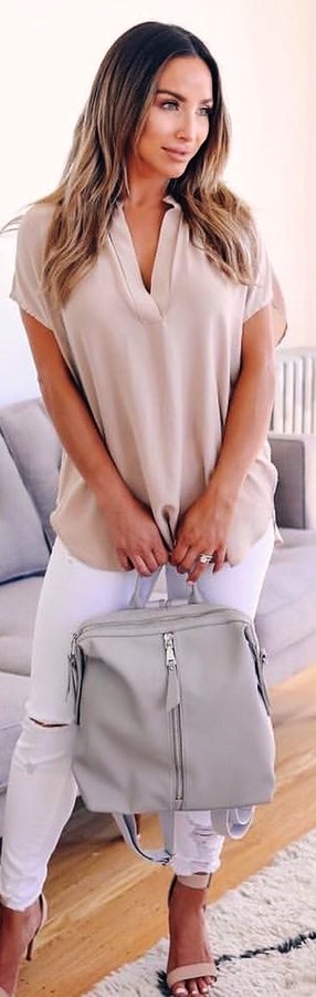 Split-neck shirt holding gray leather backpack.