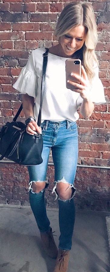 White boat-neck puff-sleeved shirt, distressed jeans, and brown heeled shoes.