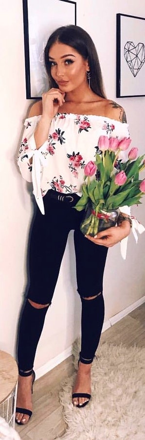 White off-shoulder top holding bouquet of flowers.