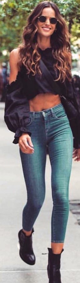 Woman in black sleeveless crop top and denim pants outfit.