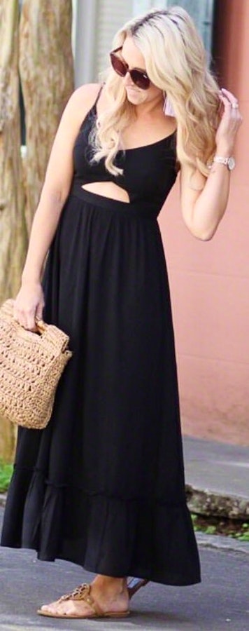 Woman in black spaghetti strap dress holding brown hand bag with black sunglasses.
