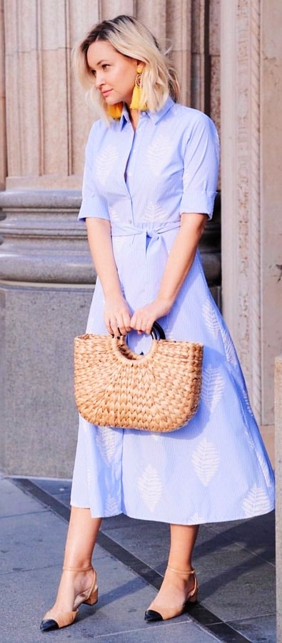 Woman in blue dress holding bag.