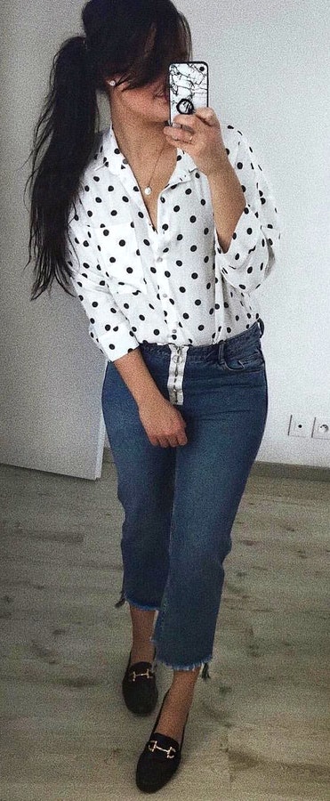 Woman with white and black polka dot long sleeved shirt and blue denim capri pants.