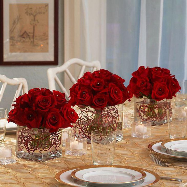 Red Rose Centerpieces in Clear Box Vases for a Christmas Party Table.