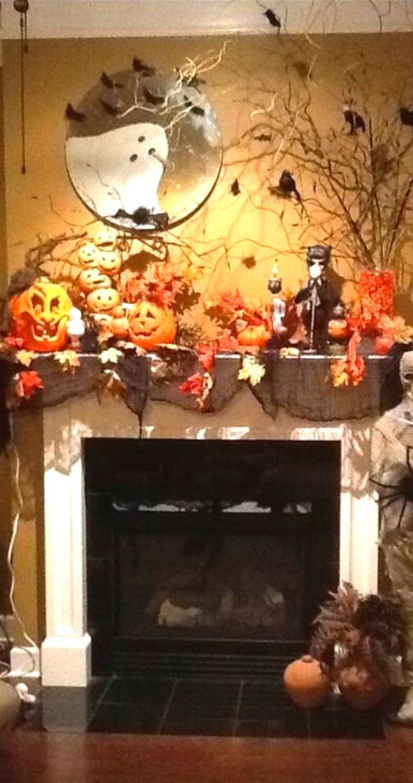 Spooky Halloween mantel decoration with skeleton spider crows pumpkins and tree.
